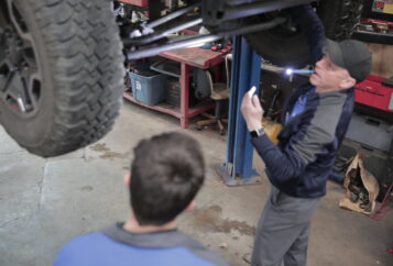 ASE certified technicians examining the undercariage to inspect for transmission and oil leaks